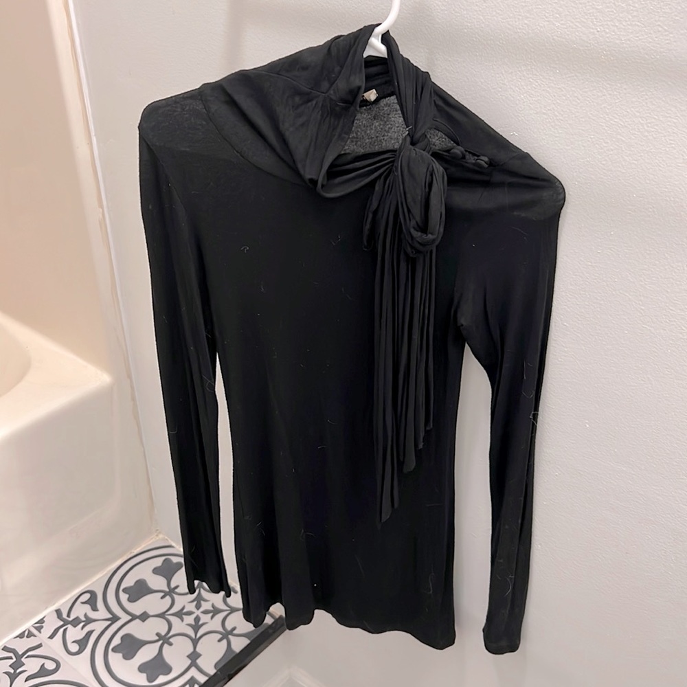 Black long sleeve blouse with accent buttons at collarbone, tie at neckline.